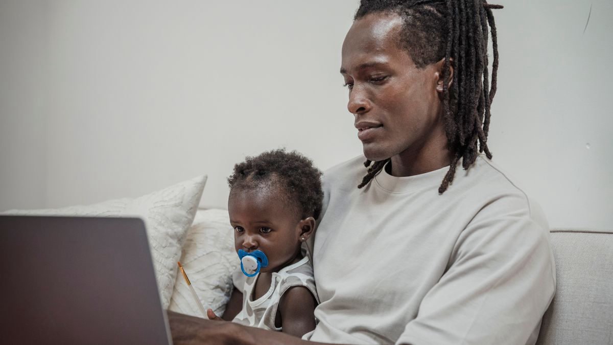 Father holding his baby while working on a laptop
