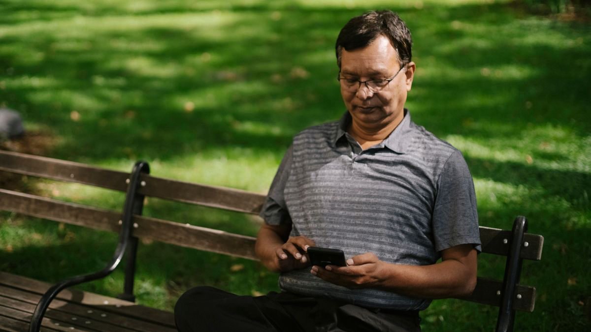 A man sitting outdoors using his smartphone