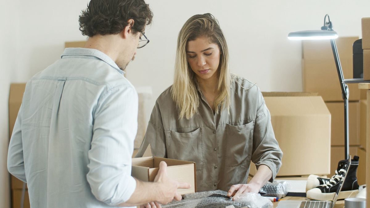 Two young people packing clothes into parcels for online orders