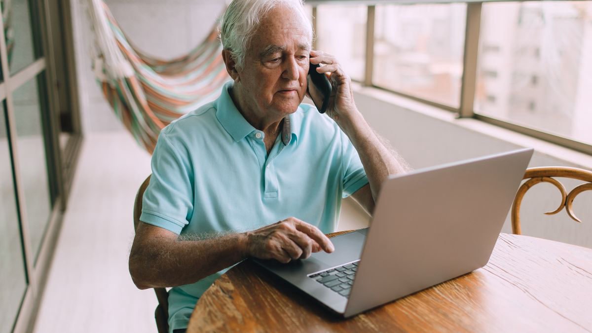 Man using a phone and a laptop together at home