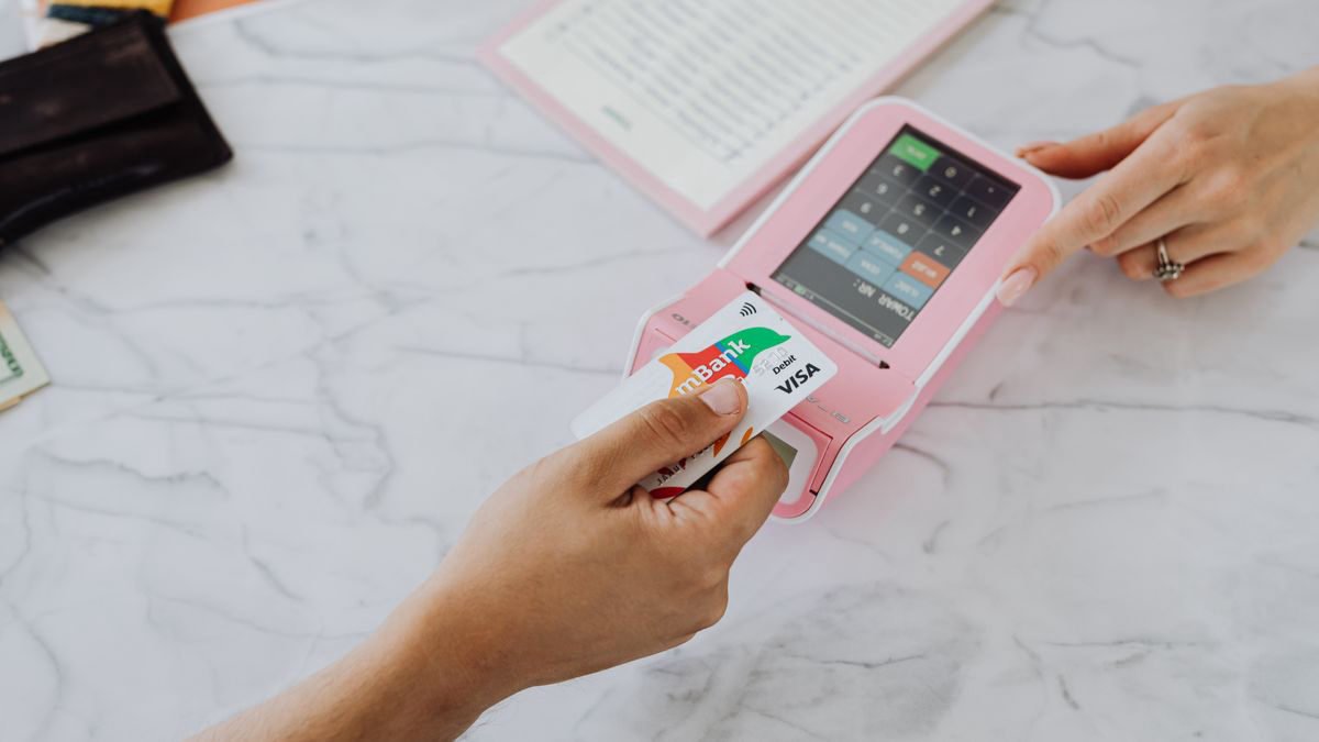 Hands making a contactless payment with a phone at a card terminal