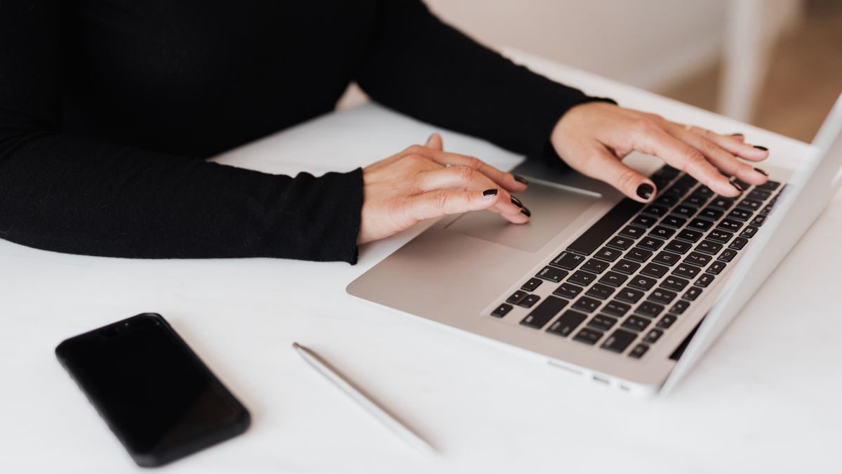 A woman typing on a laptop keyboard at a table