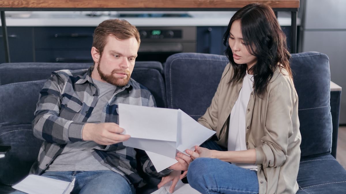 A couple sitting on a sofa going through tax paperwork together
