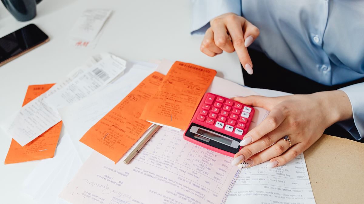 A woman adding up receipts with a calculator at her desk