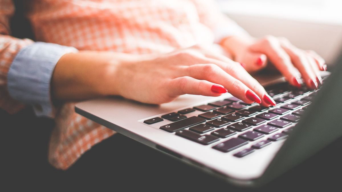 Close-up of hands typing on a laptop keyboard