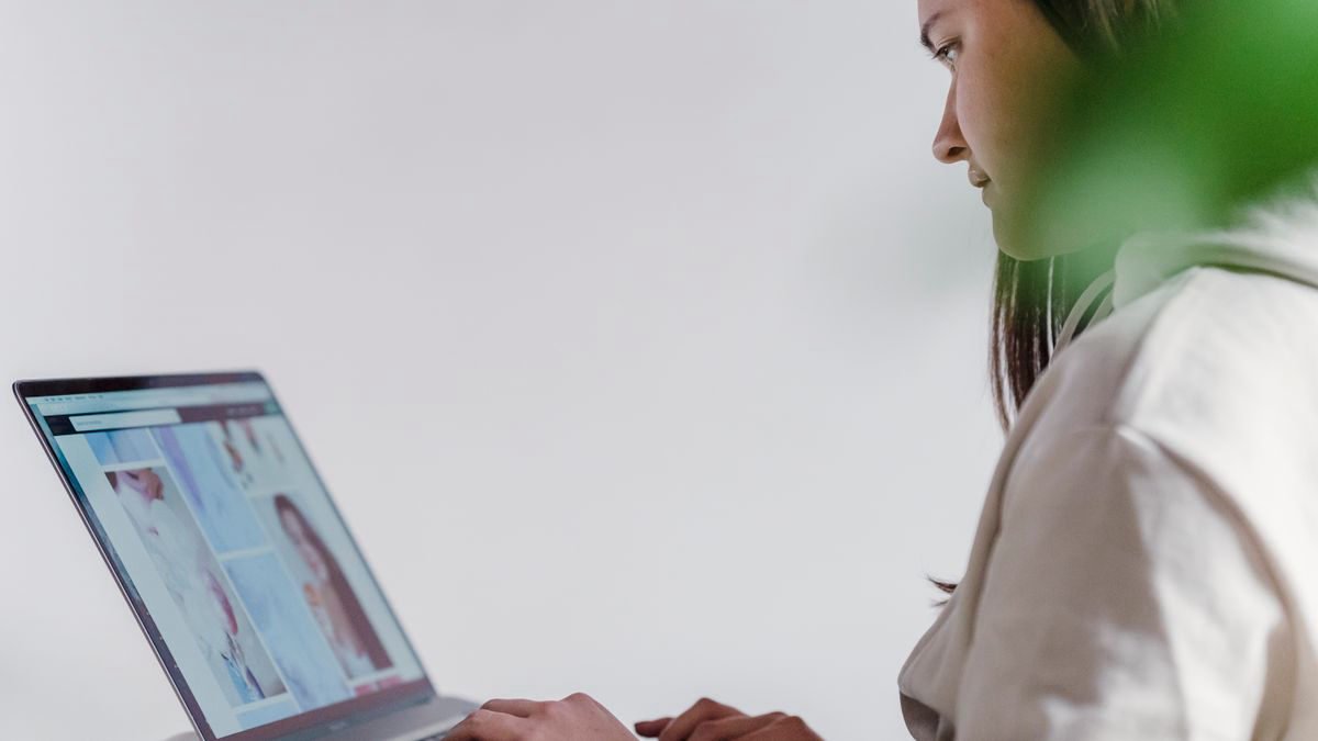 Woman typing on a laptop at a desk at home