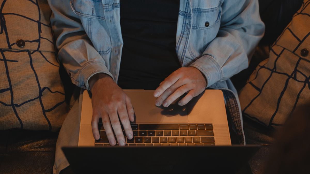Person typing on a laptop while seated comfortably indoors