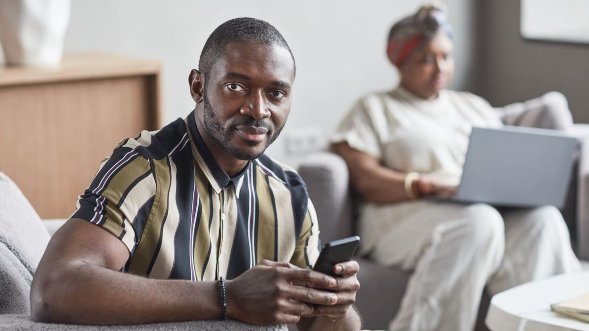 Man holding a smartphone while sitting indoors
