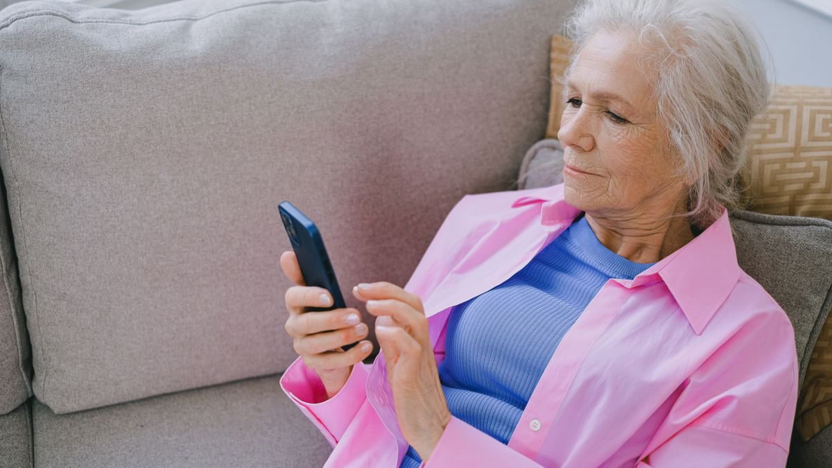 Older woman relaxing on a sofa while using her smartphone
