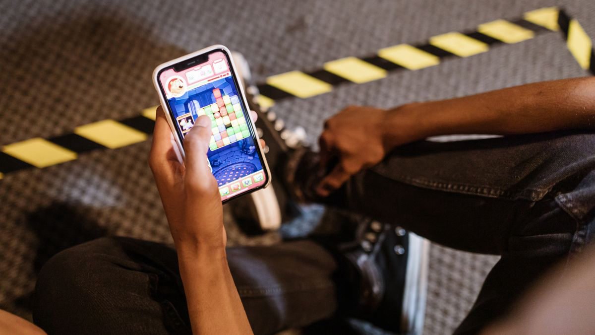 Person playing a colourful puzzle game on a smartphone indoors